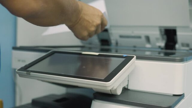 Close up, Hand of male worker press start on touch screen on photocopier machine to copy or scanning document in office. Male worker copy document at office or workplace