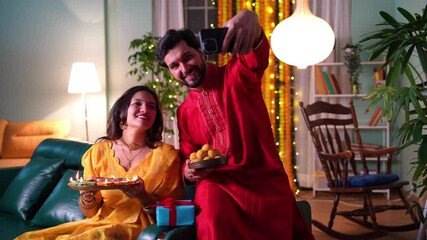A happy couple in beautiful traditional attire celebrating Diwali festival at home amidst vibrant decorations ,diyas,sweets and love filled selfies. 
