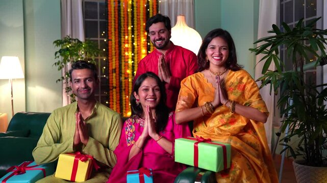 A joyful Indian family of four in traditional  attire smiles together,exchange gifts and warm wishes during a heartwarming Diwali celebration in their well decorated home.