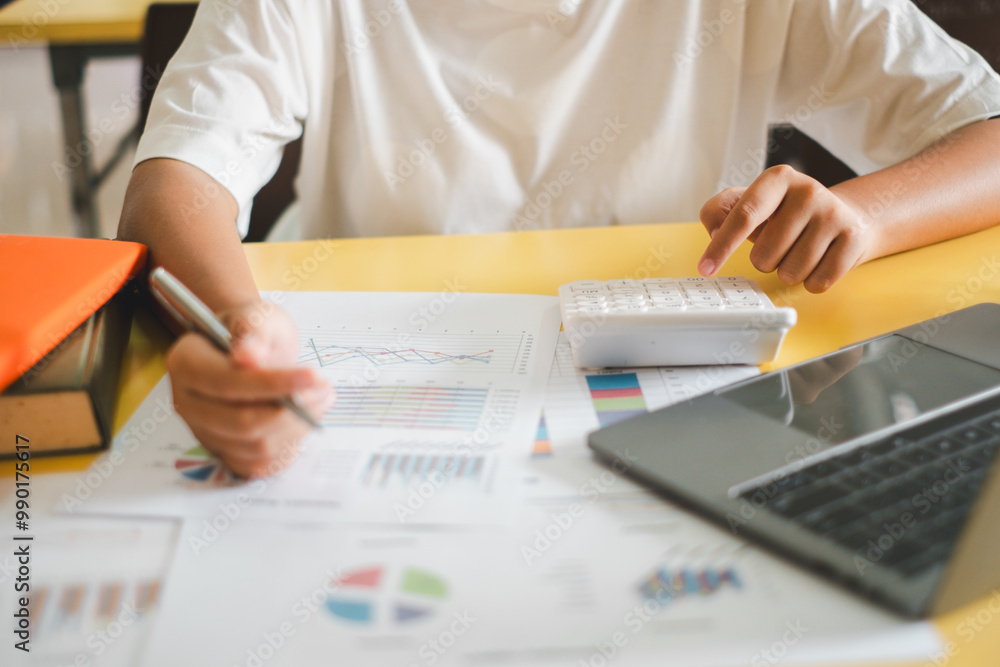 Poster close-up of a businessperson using a calculator and reviewing financial charts and graphs on a desk 