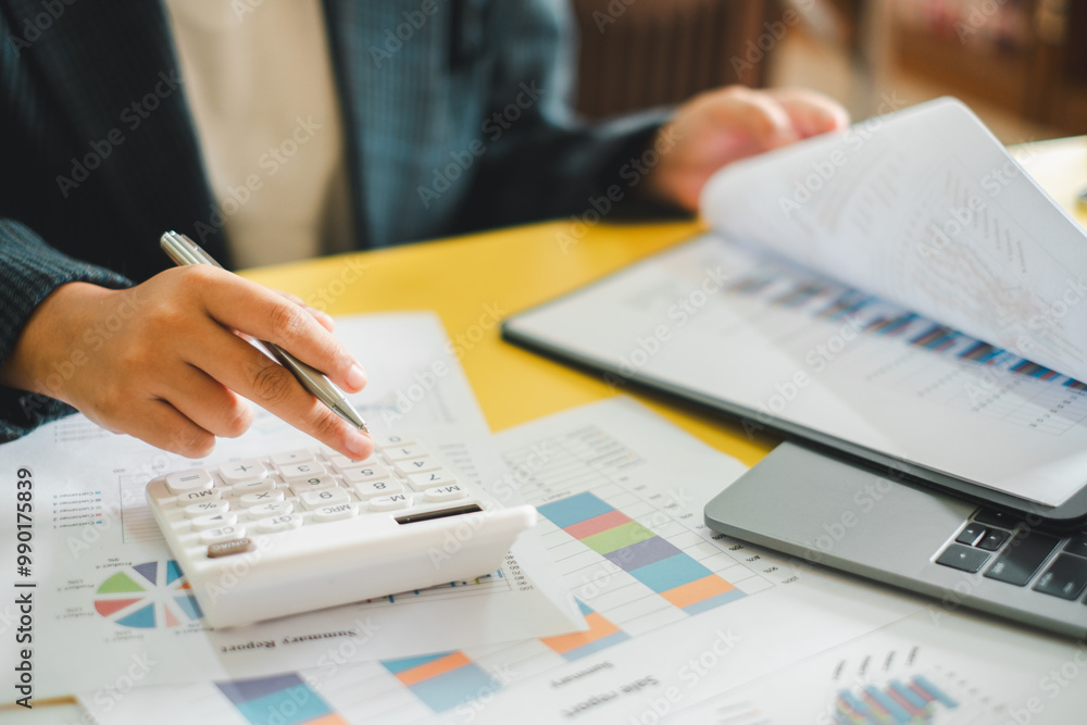 Poster a business professional using a calculator and reviewing financial documents at a desk, focusing on 