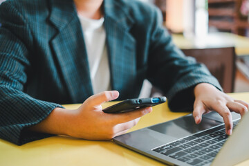 Fototapeta premium Close-up of a business professional using a smartphone and laptop, highlighting modern technology in a professional environment.