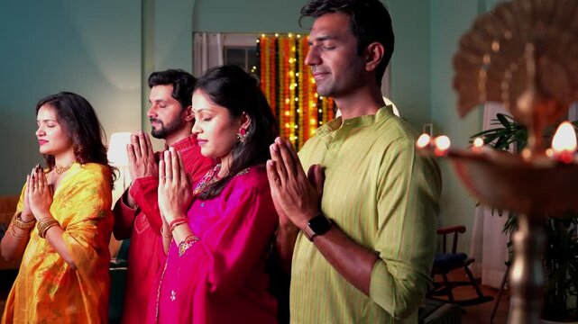 An Indian family dressed traditionally,lights samai and prays with folded hands seeking divine blessings for love and togetherness