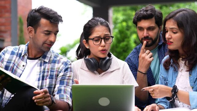 Indian group of stuents in western outfits  gather on college lawns discussing and helping each other solving a difficulty while laughing at silly mistakes