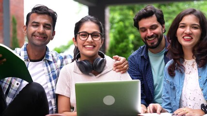 Indian students enjoying their free time on college grounds as they laugh heartily at funny quotes and jokes while using laptops and sharing books in a lively atmosphere