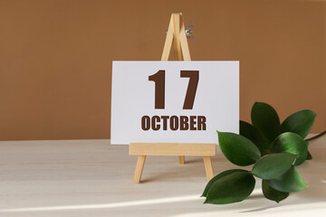 October 17th. Day 17 of month, Calendar date. Green branch, easel with the date and month on...