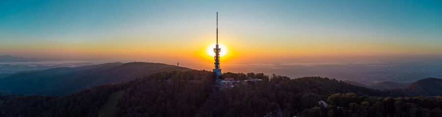 Obraz premium Early morning sunrise panorama of Sljeme above Zagreb with visible antenna tower, big massive hill and layers of fog below in valley. Epic panorama above zagreb