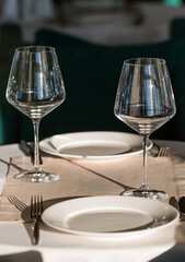 Stylish table setting. Glass glasses, plates, cutlery on the table. Wedding service, reception at the dining table. A birthday, a baptism, a festive event.