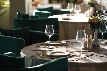 Stylish table setting. Glass glasses, plates, cutlery on the table. Wedding service, reception at the dining table. A birthday, a baptism, a festive event.