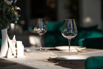 Stylish table setting. Glass glasses, plates, cutlery on the table. Wedding service, reception at the dining table. A birthday, a baptism, a festive event.