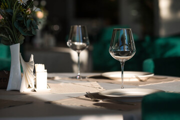 Stylish table setting. Glass glasses, plates, cutlery on the table. Wedding service, reception at the dining table. A birthday, a baptism, a festive event.