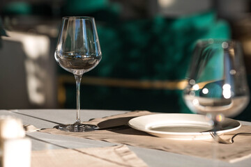 Stylish table setting. Glass glasses, plates, cutlery on the table. Wedding service, reception at the dining table. A birthday, a baptism, a festive event.