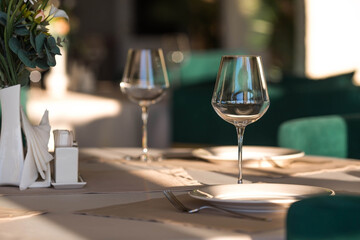 Stylish table setting. Glass glasses, plates, cutlery on the table. Wedding service, reception at the dining table. A birthday, a baptism, a festive event.