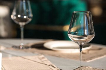 Stylish table setting. Glass glasses, plates, cutlery on the table. Wedding service, reception at the dining table. A birthday, a baptism, a festive event.