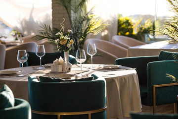 Stylish table setting. Glass glasses, plates, cutlery on the table. Wedding service, reception at the dining table. A birthday, a baptism, a festive event.