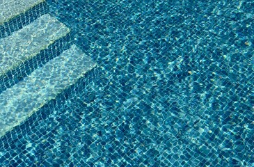 A high angle view of steps leading down into a tiled swimming pool. 