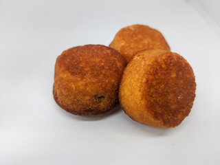 A close-up view of three small, round, golden brown muffins on white surface.