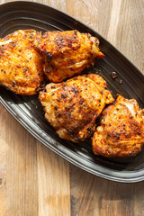 Fried chicken with hot thai bbq seasoning on a black stoneware dish. On wooden background