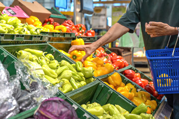 Mature man chooses yellow bell peppers in supermarket