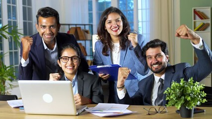 A young Indian group of businessmen or professionals is working together in the office, expressing their happiness and satisfaction after achieving great results and success on their latest project