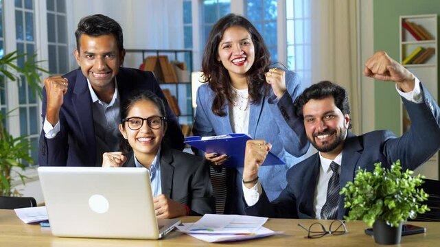 A young Indian group of businessmen or professionals is working together in the office, expressing their happiness and satisfaction after achieving great results and success on their latest project