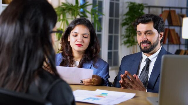 Indian businesswoman in a modern office setting,  reviewing the work and project documents prepared by her team members, ensuring accuracy and providing feedback on their progress