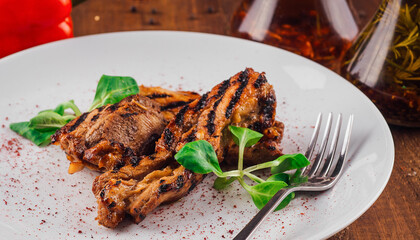 Grilled chicken breast on white plate being served on wooden table