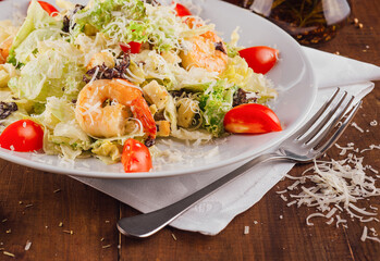 Caesar salad with shrimps being served on a white plate