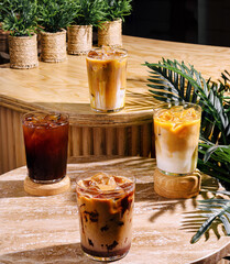Four iced coffee drinks sitting on a cafe table in the sun