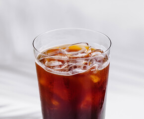 Cold brew coffee standing on white cube with tropical plant shadow