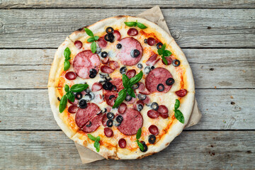 Pizza with mozzarella cheese , salami sausages , olives , and basil