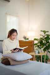 Young asian women in sweater sitting on comfortable couch to enjoying and happiness with reading...