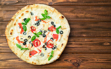 Pizza with mozzarella cheese , olives , chicken , pineapple , basil and tomatoes