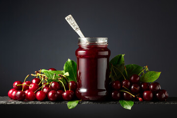 Cherry jam and fresh berries on a black background.