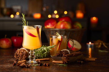 Mulled cider with apples, cinnamon, rosemary, and anise on a background of burning candles.