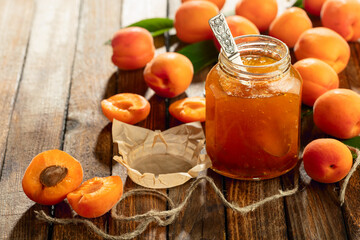 Apricot jam and fresh fruit on an old wooden table.
