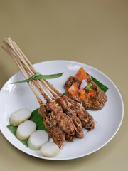 Sate Ayam Madura or Madurese chicken satay, Indonesian popular dishes. Skewered and grilled chicken, served with peanut sauce. and addition of rice cake, shallot and chili chops