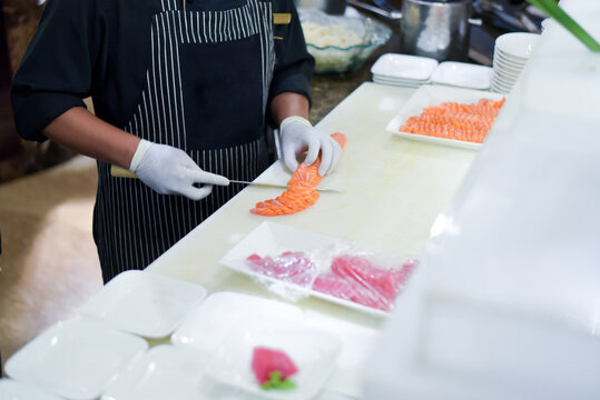 Chef use knife preparing a fresh salmon on a cutting board, Japanese chef in restaurant slicing raw salmon, ingredient for seafood dish. Chef with a knife cutting raw salmon