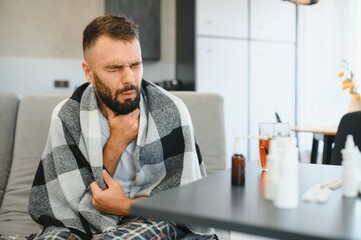 Sick man holding his chest in pain while coughing in the living room. Sore throat and cough, man...