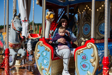 Mother and child enjoying a colorful carousel ride at the park