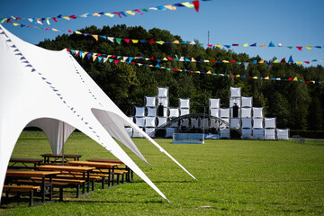 Outdoor festival setup with stage and white tents in a green field