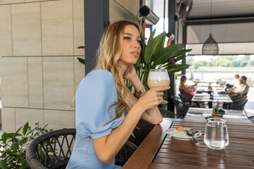 Beautiful woman sitting alone in the cafe bar drinking coffee, waiting for someone