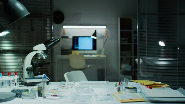Workplace of forensic scientist with microscope, evidence bags, test tubes and examination tools on table in crime lab with no people