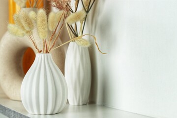 Minimalistic arrangement featuring a white ceramic vase with dried ornamental grasses on a clean, neutral-toned surface. Ideal for home decor inspiration, modern interiors, or lifestyle photography.