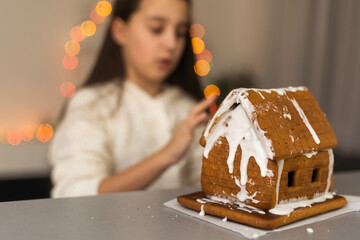 A girl plays with a gingerbread house for traditional Christmas decoration