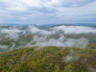 Aerial drone view flying over misty forested mountains in Strandzha National Park, Bulgaria. Foggy landscapes and green forests create a peaceful, mystical atmosphere in nature