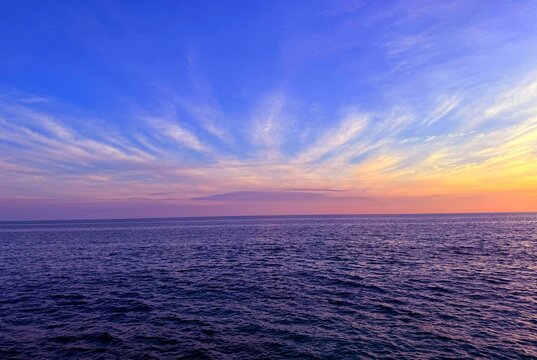 Dusk  heaven clouds over dark blue ocean waters.