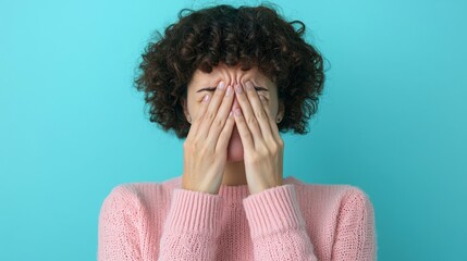 Person with Curly Hair Hiding Face with Hands