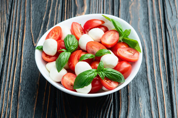 Basil leaves , cherry tomatoes and mozzarella cheese . In bowl food photography