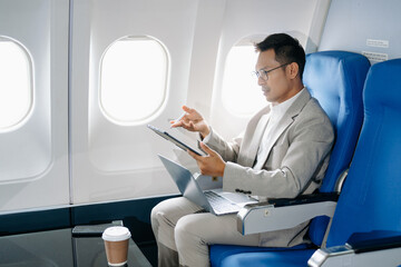 Asian man sitting in a seat in airplane and looking out the window going on a trip vacation travel concept.